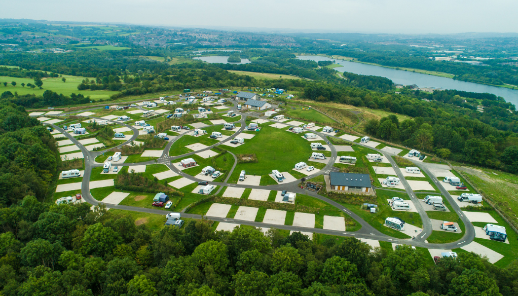 An aerial view of a large field with lots of motorhomes and cars on it.