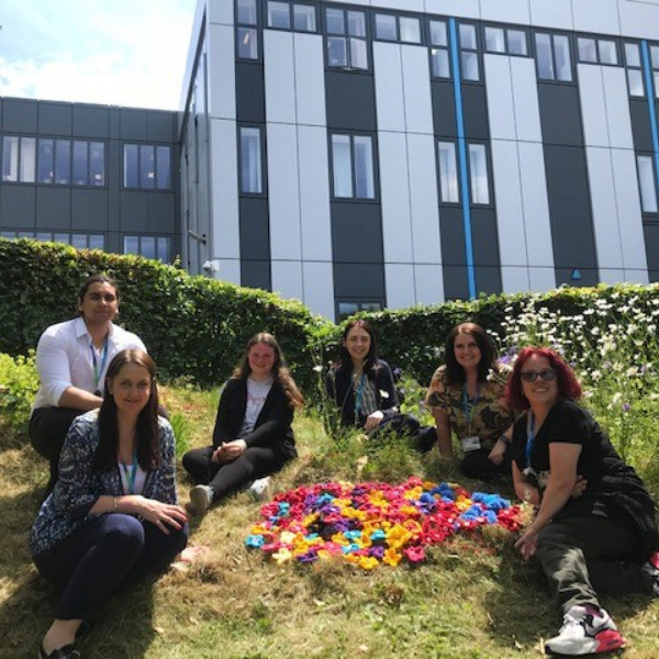 Group of knitters in front of Rotherham College with knitted flowers