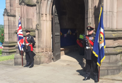 Two cival service men standing outside the rotherham minster with flags